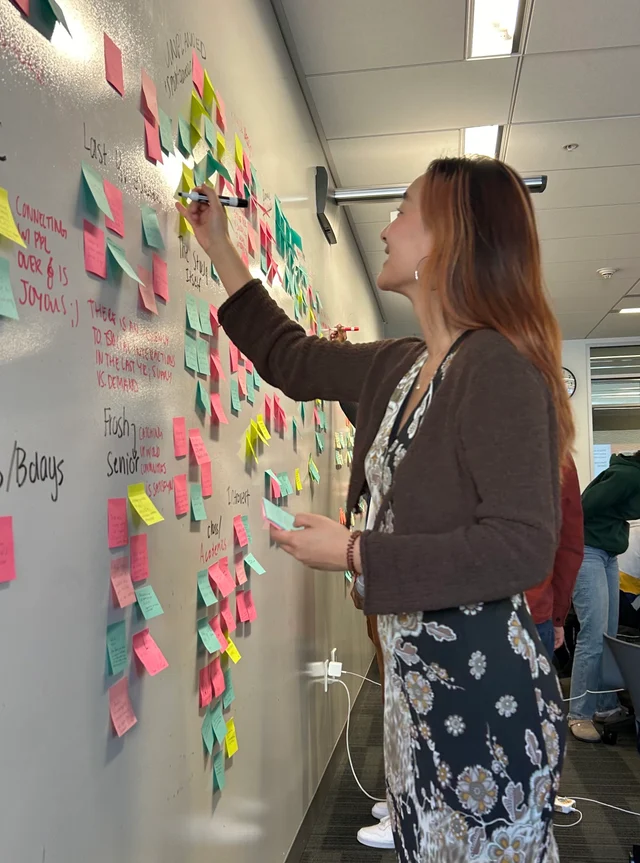 Jin-Hee Lee in a design thinking exercise with post-its on the wall to group brainstorm solutions